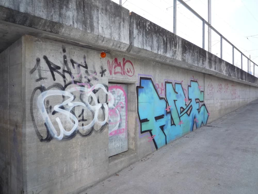 Mit Graffiti besprühte Betonwand vor der Sanierung durch Bezzola Flavio AG